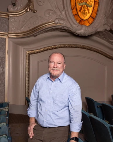 Man in blue shirt standing in theatre