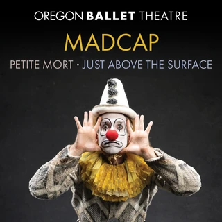 A clown in black-and-white stripes and a yellow ruff poses playfully with hands framing a painted face. Text reads "Oregon Ballet Theatre: Madcap, Petite Mort, Just Above the Surface." The tone is whimsical and theatrical.