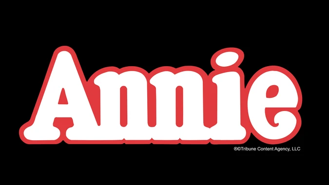 "Annie" title art image featuring the word "Annie" in bold white text with a red outline against a black background. The style is playful and vibrant.