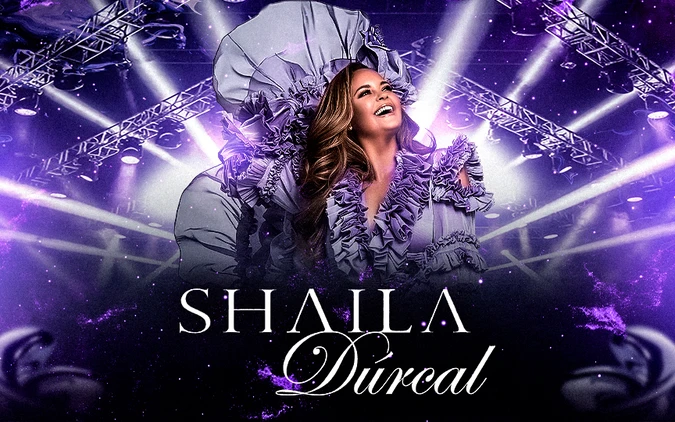 A woman in an elaborate purple dress smiles joyfully, surrounded by vibrant concert lights and stage rigging. The text reads "Shaila Dúrcal" in elegant font.