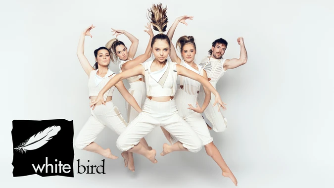 Five dancers in white outfits leap in unison against a white background. Their expressions are focused and energetic. A black logo with a white feather and the words "white bird" is in the bottom left corner.